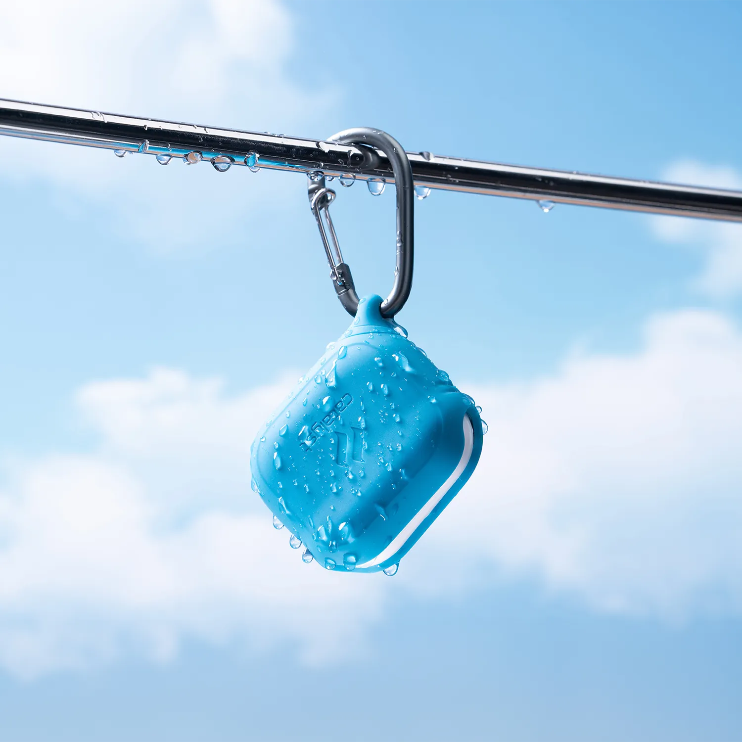 The Catalyst Case US AirPods (Gen 3) Waterproof Case + Carabiner is a rugged, blue, square-shaped case hanging from a metal rail under bright skiesâ€â€Âideal for outdoor use and built to protect your AirPods against the elements.