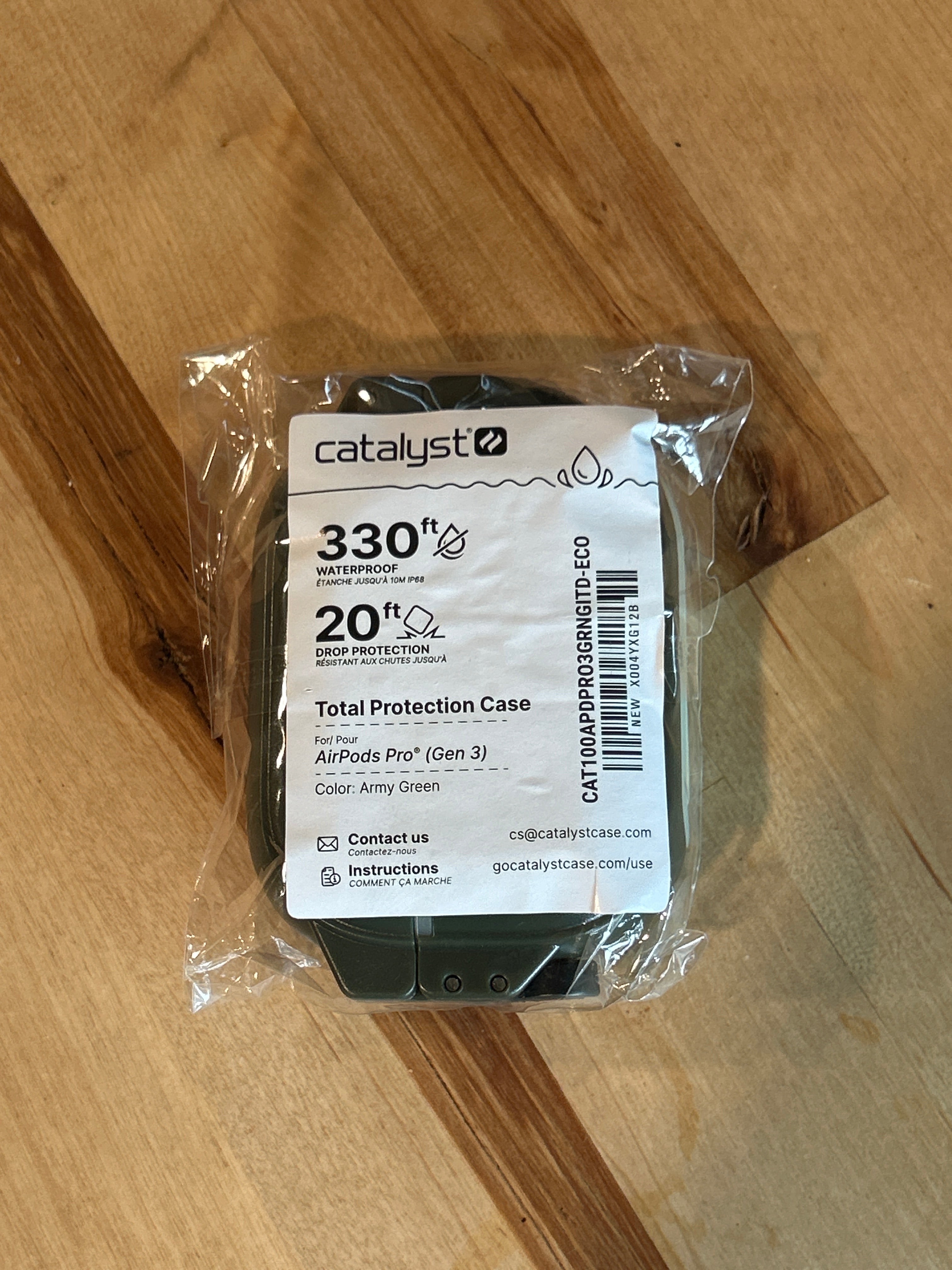 Green Glow-in-the-Dark Catalyst Case US AirPods Pro 3 – 100M Waterproof Total Protection Case + Carabiner, shown in sealed plastic packaging on a wooden surface. This waterproof case for AirPods Pro offers military-grade drop protection and features a label indicating 330ft waterproof and 20ft drop protection ratings.