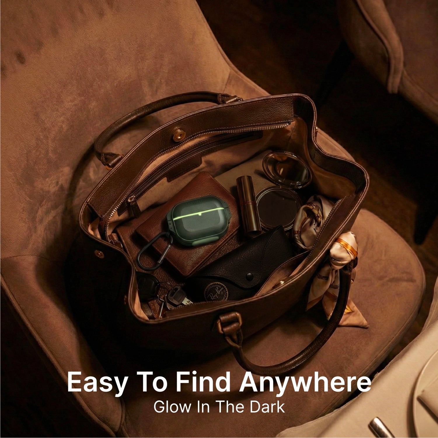 A brown leather handbag sits on a chair. Inside, a glowing green Catalyst Case US AirPods Pro 3 - 100M Waterproof Total Protection Case + Carabiner stands out among sunglasses, lipstick, wallet, and keys. “Easy To Find Anywhere. Glow In The Dark.”.
