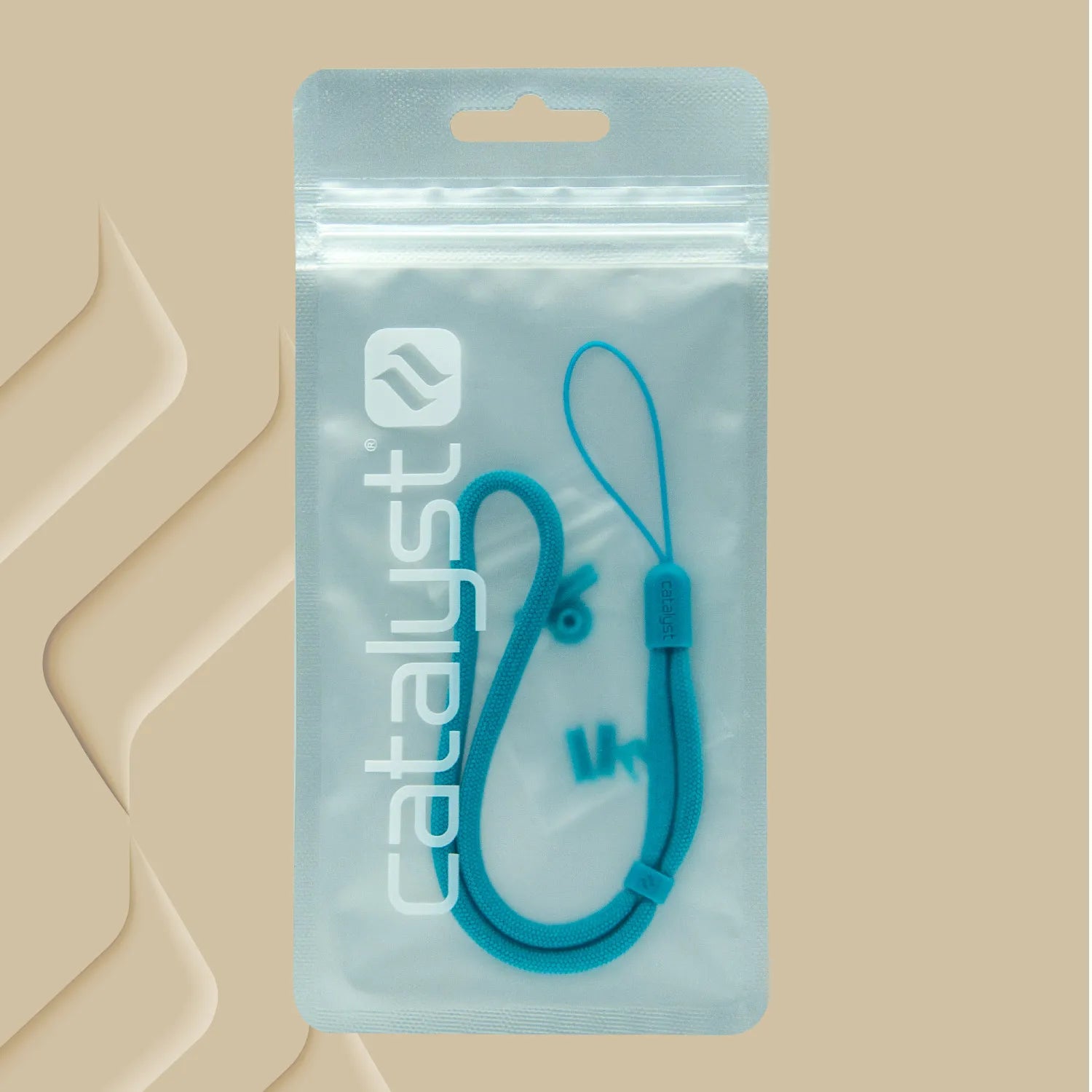 A blue lanyard with adjustable slider and loop from Catalyst Case US is shown inside a clear, resealable pouch labeled “catalyst” in white text. The tan background features subtle abstract patterns on the left side. Product: Colored Lanyard & Buttons.