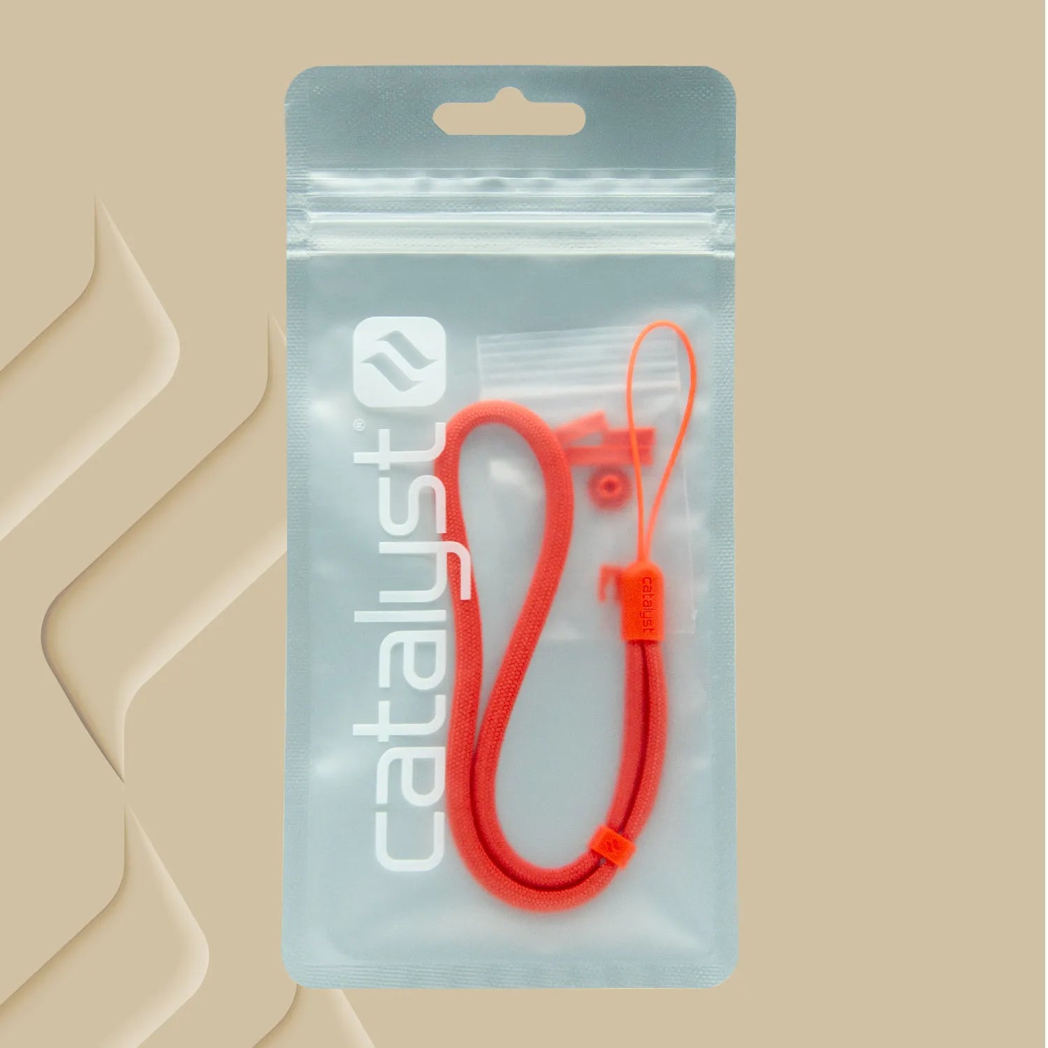 The Colored Lanyard & Buttons by Catalyst Case US includes a red wrist strap with clasp, packaged in a clear ziplock bag featuring the brand's logo and "catalyst" in white text. The packaging has a beige background with abstract shapes on the left.
