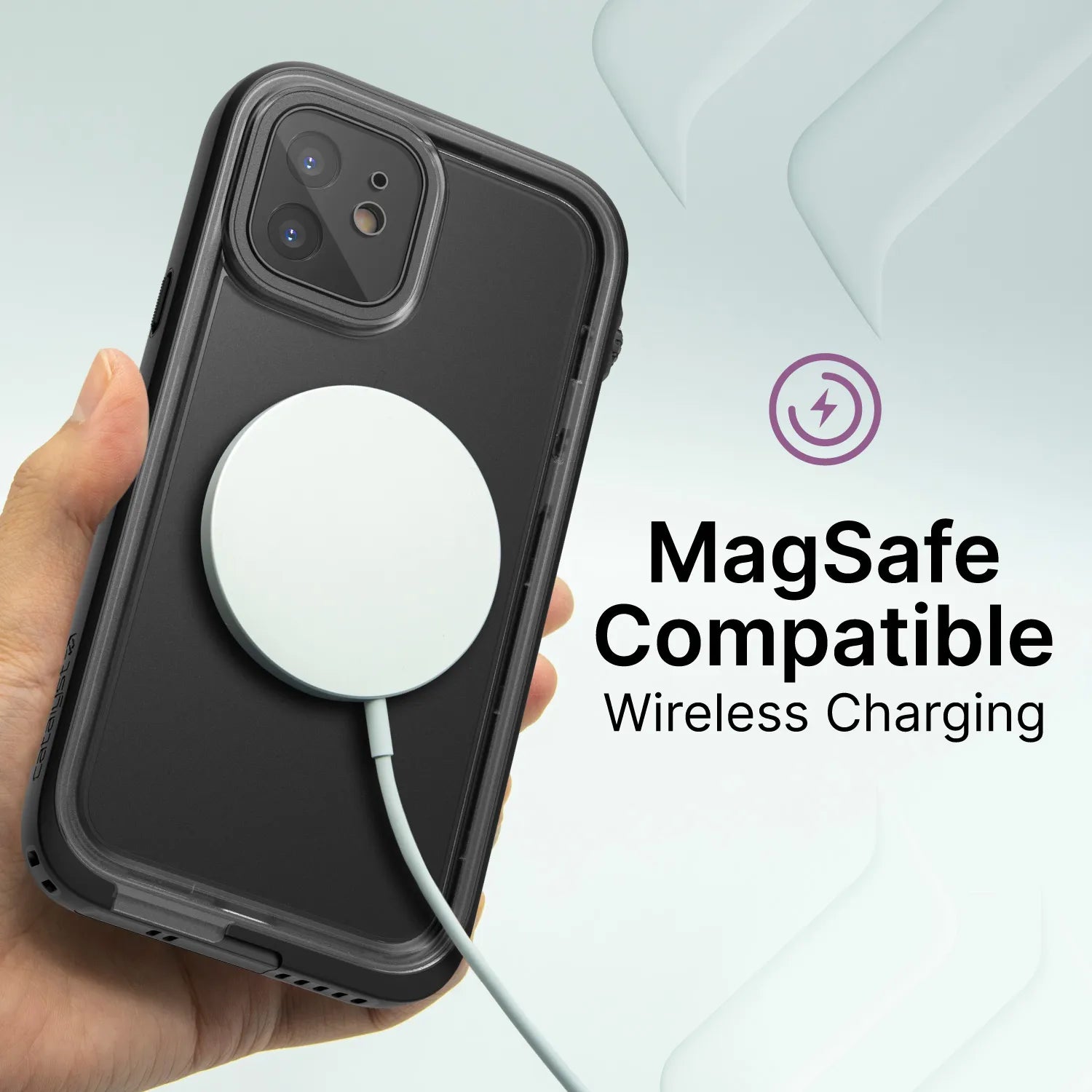 A hand holds an iPhone 12 in a black Catalyst Case US waterproof case with a MagSafe charger attached. The screen displays “MagSafe Compatible Wireless Charging” next to a purple charging icon, with light graphics in the background.