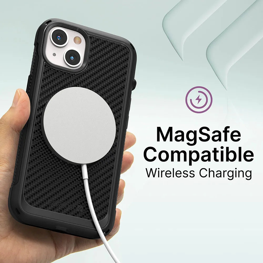 A hand holds an iPhone 13 with the Catalyst Case US Vibe Case in textured black and a round, white MagSafe charger. On the right, text reads "MagSafe Compatible Wireless Charging" with a charging icon and soft green shapes behind.