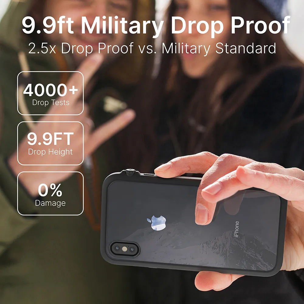A hand displays the Catalyst Case US iPhone Xs Max - Impact Protection Case in black. In the blurred outdoor background, two people smile, one flashing a peace sign. Text highlights 9.9ft military drop proof, 4000+ drop tests, and 0% damage.