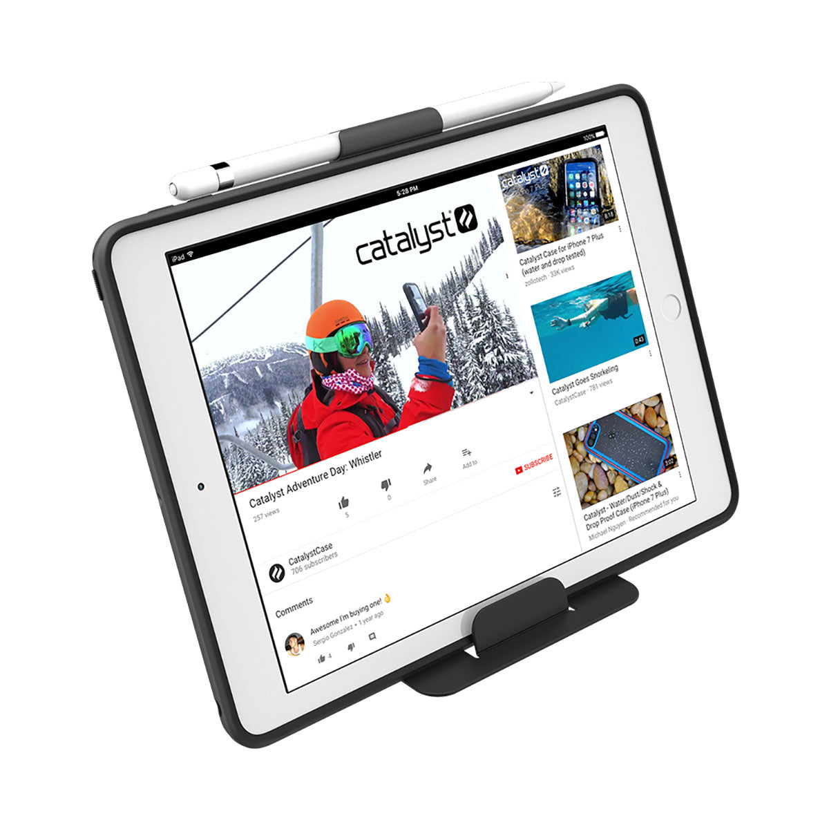 A white iPad (Gen 6/5), 9.7" in a Catalyst Case US Impact Protection Case stands upright with a stylus on top, displaying a YouTube video titled “Catalyst Adventure Day: Whistler,†featuring ski lift scenes and drop protection.