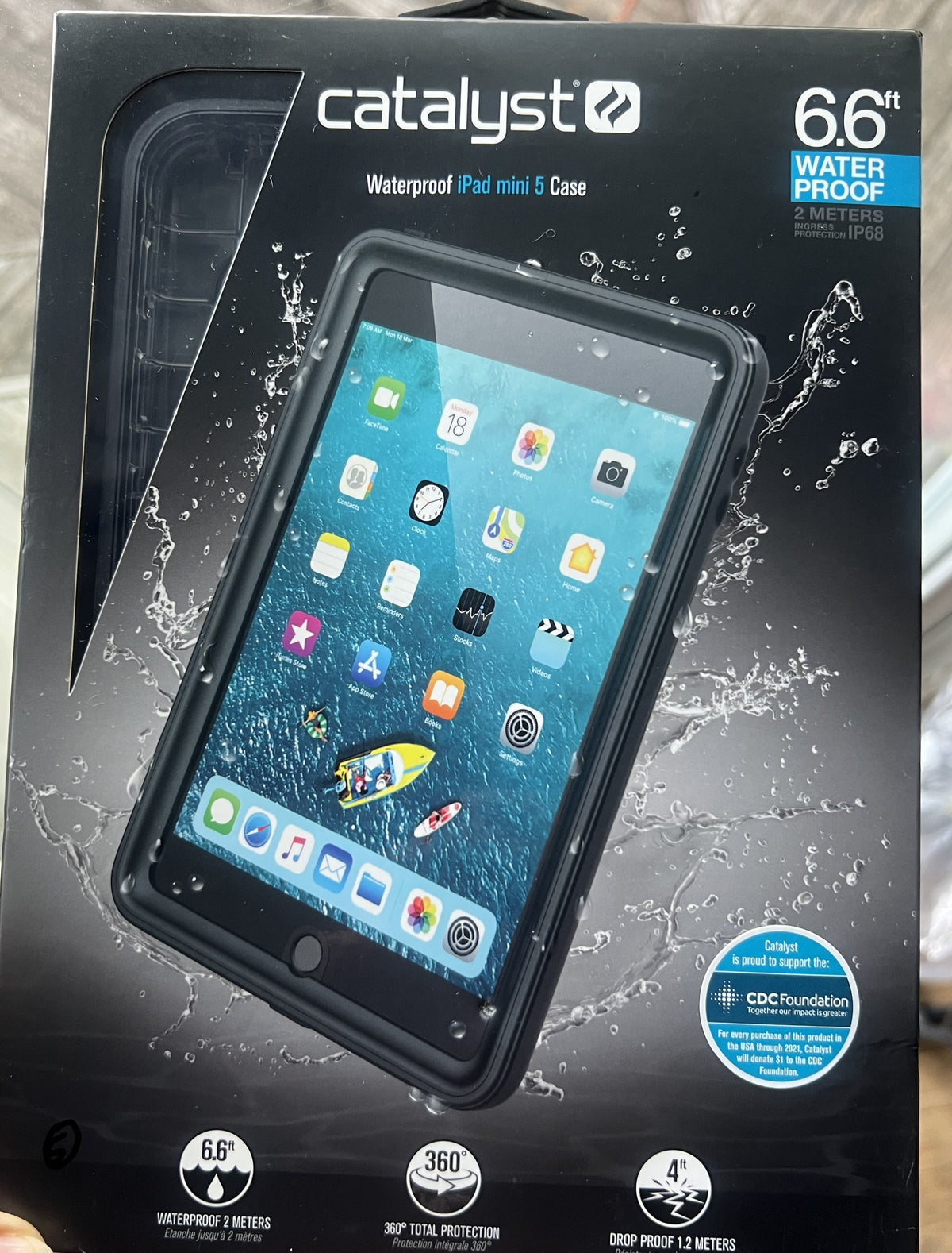 Box for a Catalyst Case US iPad mini 5 – Waterproof Case. The front displays the rugged case safeguarding an iPad Mini 5 with visible water droplets. Text on the packaging highlights key features: 6.6 ft waterproof, 4 ft drop proof, 360° protection, and support for the CDC Foundation.