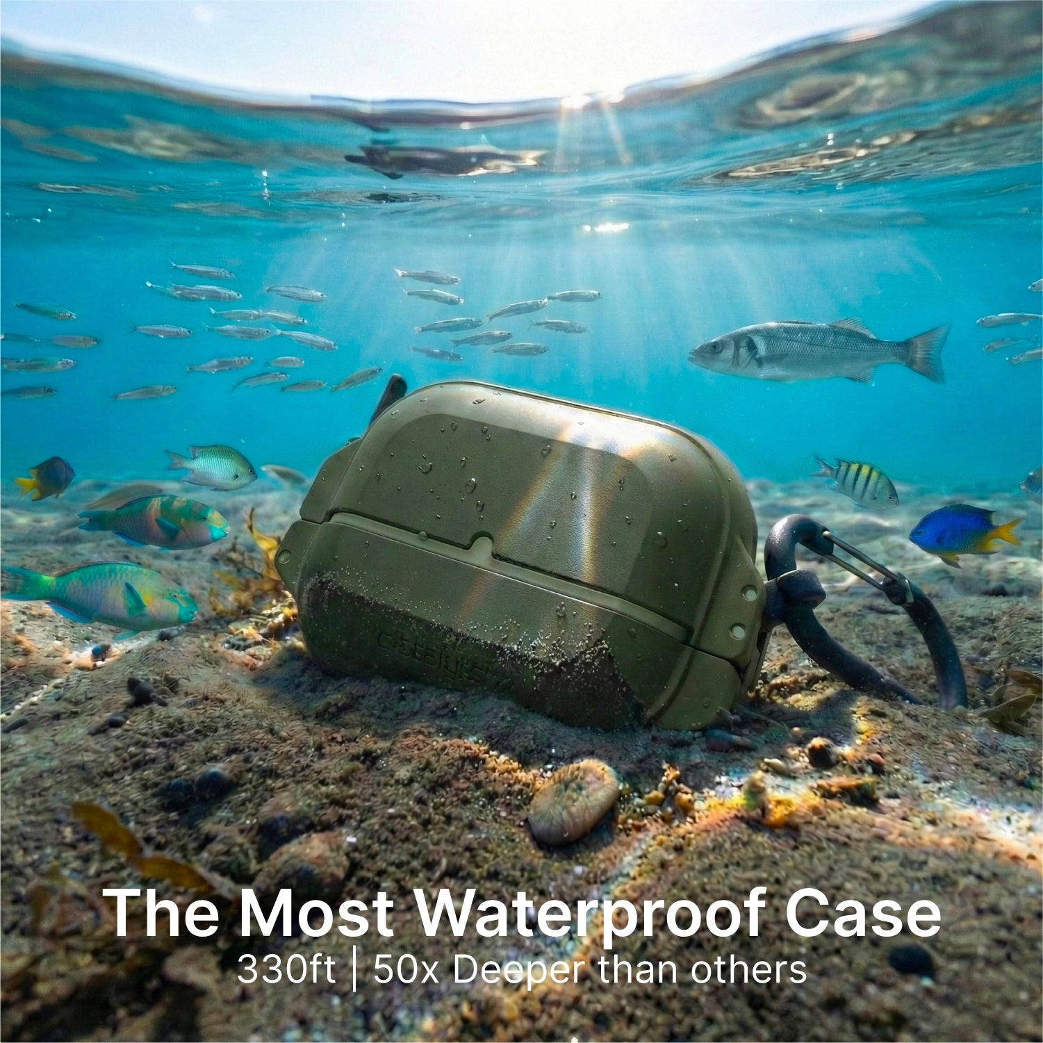 A rugged green Catalyst Case US AirPods Pro 3 - 100M Waterproof Total Protection Case + Carabiner rests on a sandy seabed among rocks, plants, and fish. Sunbeams filter down. Text: "The Most Waterproof Case—330ft | 50x Deeper than others.